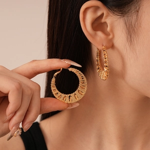 Boucles d'oreilles créoles dorées à texture tressée portées par un mannequin