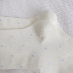 Détail de chaussettes en coton blanc à pois bleu clair et texture tricotée