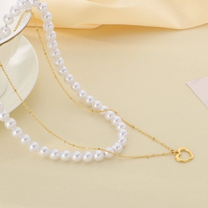 Detail of double-layer gold necklace with white baroque pearls and hollow heart pendant
