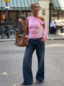 Débardeur rose à bretelle unique, jean large bleu et grand sac à main en daim marron