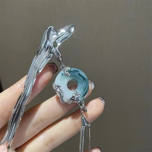 Silver hair pin with green jade donut pendant and long tassels in a handheld view
