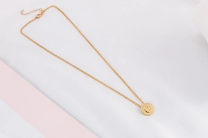 Detailed shot of gold-plated titanium necklace with polished round letter C pendant