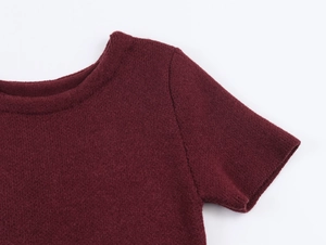 Detail view of burgundy knitted top featuring round neck and fine ribbed texture