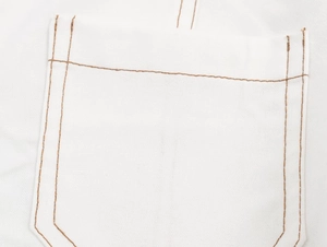 Vue macro détaillée du denim blanc avec coutures contrastées marron sur la poche