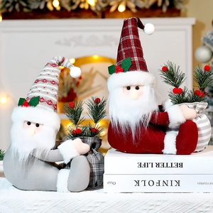 Festive Santa figurines with red and grey hats on books near a warm fireplace