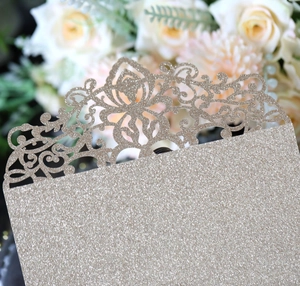 Macro shot of laser-cut floral patterns and champagne gold glitter texture on invitation