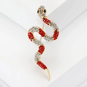Macro shot of gold snake brooch with crystal rhinestones on white geometric block