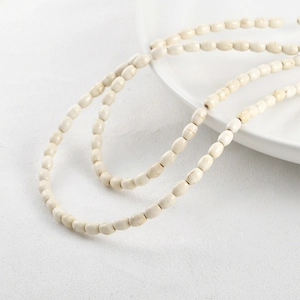 Minimalist cream white rice-shaped stone beads necklace on textured white surface