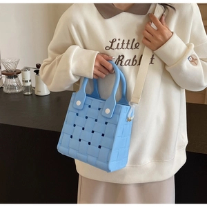 Detail of light blue EVA woven handbag showing hollow design and adjustable strap texture