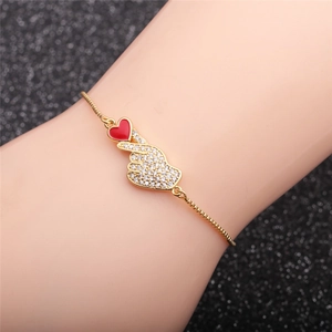 Detail of hand gesture bracelet with red enamel heart and white cubic zirconia accents