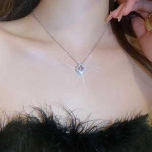 Close-up of a silver clover pendant necklace with pink zircon on a model's neck