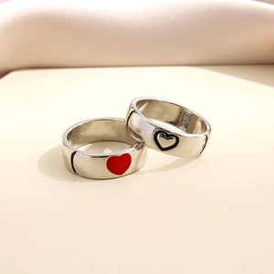 Detail of silver couple rings featuring a red solid heart and a black outline heart