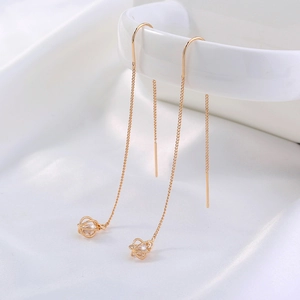 French style gold zircon tassel earrings with hollow sphere pendant on white silk background