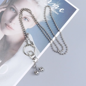 Detailed view of silver cherry keychain with bead chain and clasp on a fashion magazine