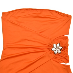Détail de robe bustier orange avec boucle fleur en métal doré et plissage sophistiqué