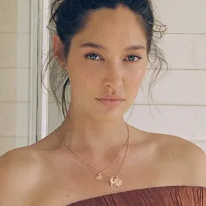 Double-layered gold stainless steel necklace with coin and shell pendants on female model
