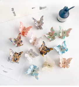 Flat lay of thirteen colorful marble patterned butterfly hair claws on artistic background