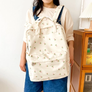 Close-up of cream floral canvas backpack featuring pink rose patterns on girl's back