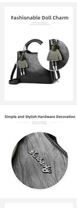 Detail of black textured leather handbag with unique doll charm and silver metal logo