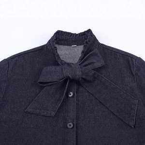Dark blue denim shirt featuring a ruffled stand collar and large bow tie accent