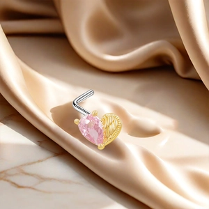 Close-up of heart-shaped piercing with pink zircon and golden wing texture detail