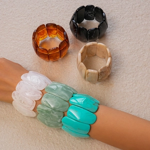Detailed close-up of colorful marble texture acrylic resin wide bracelets set on stone
