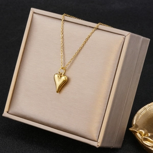 Detailed view of a golden 3D heart pendant necklace displayed in a beige jewelry box