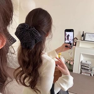 French vintage style black polka dot chiffon bow hair clip shown on model in a cozy setting