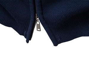 Detailed macro shot of a dark blue knit cardigan with a grey metallic zipper closure