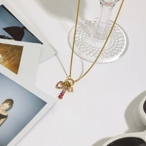 Detail of gold heart and key pendants with pink stones on a stainless steel necklace