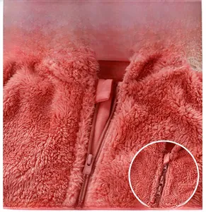 Détail de la double fermeture éclair sur une combinaison bébé en peluche rose toute douce