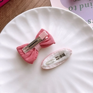 Detail von rosa Stoffschleife-Haarspange und gestrickter Haarnadel auf Keramiktablett