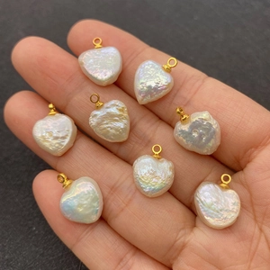 Handheld view of heart-shaped natural freshwater pearl pendants with golden rings