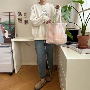 Borsa tote in tela tie-dye rosa e bianca con tasca esterna mostrata in un ambiente domestico