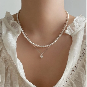 Close-up of elegant double-layer necklace with white pearls and a bow pendant