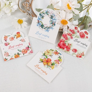 Close-up of four watercolor floral greeting cards with Best Wishes text on textured cloth