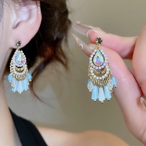 Detailed close-up of bohemian fan-shaped earrings with golden chain tassels and teardrop gems