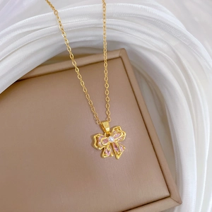 Macro view of gold bow pendant with pink stones and central pearl on necklace