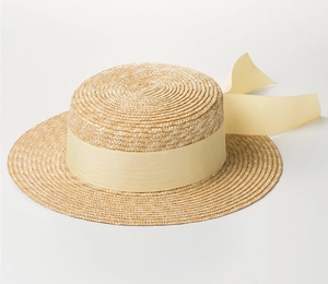 Detail of hand-woven wheat straw boater hat with a wide ribbon and elegant bow accent