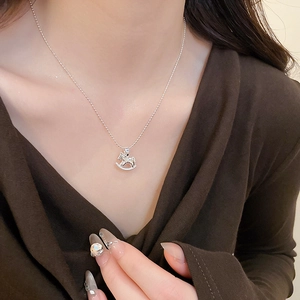 Detail shot of a silver rocking horse pendant necklace on model's neck