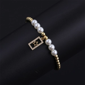 Detail of gold pearl bracelet featuring a micro-set zircon star pendant on black backdrop