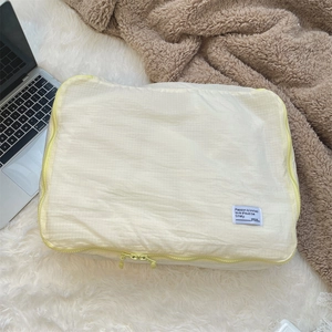 Close-up of a pale yellow checkered waterproof travel organizer with a zipper and fabric label