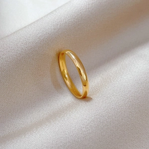 Macro detail of high-polish gold minimalist titanium ring on white satin fabric