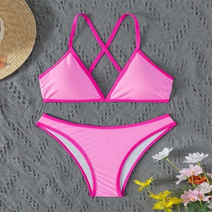 Detail of pink two-piece bikini set with criss-cross back straps on grey textured fabric