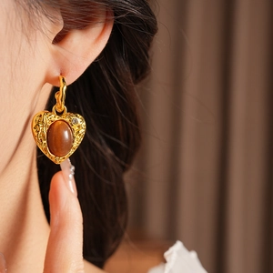 Close-up of vintage resin heart earrings with brown oval stone and retro gold details