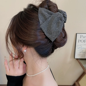 Detail of a large black acrylic hair claw clip with silver rhinestones on a bun hairstyle