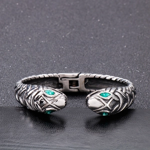 Macro shot of silver snake cuff bracelet featuring green gemstone eyes and scale details