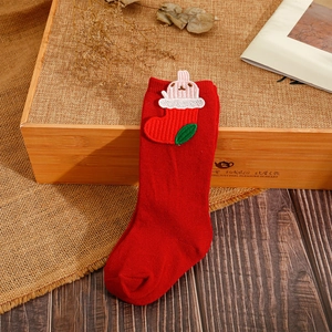 Detail of red Christmas socks featuring a 3D bunny embroidery on a rustic wooden box