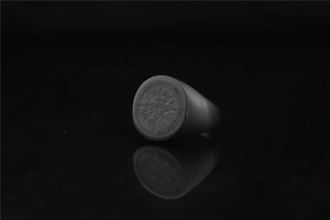 Macro shot of matte black compass star ring with Lucleon engraving and mirror reflection