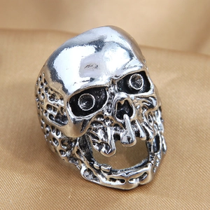 Macro shot of silver punk skull ring with vintage distressed finish on gold fabric